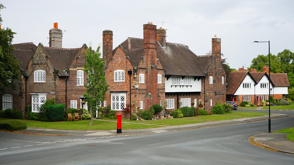 A large, multi-story red-brick building with a traditional architectural style, featuring a series of gabled roofs with dark roofing tiles and multiple prominent chimneys. The building has numerous wh