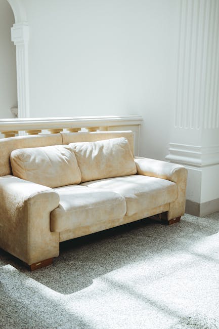 A weathered, vintage wooden sofa with an ornate carved backrest and brown upholstered fabric cushion, positioned directly in front of a large, densely packed wall of mixed waste paper and cardboard, w