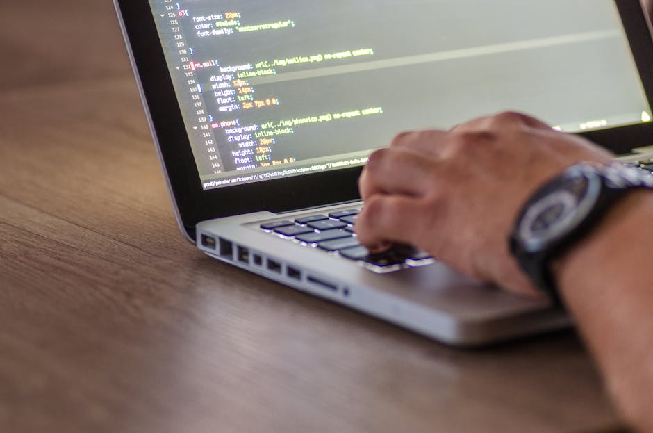 A close-up view of a laptop screen displaying lines of code written in a programming language, with visible text including variables, functions, and comments. The screen features a white background wi